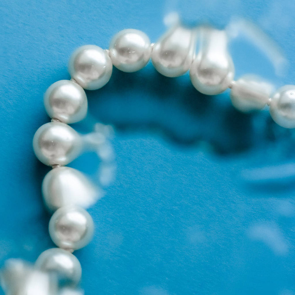 Moda de joyería costera, collar de perlas bajo respaldo de agua azul
 - Foto, Imagen