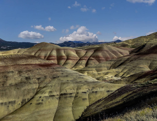 Dýchání a barevné malované kopce pokryté červenými, hnědými, černými, oranžovými a žlutými pruhy na částečně zakaleném podzimním dni na Fosilní lůžka John Day v Mitchellu Oregonu - Fotografie, Obrázek