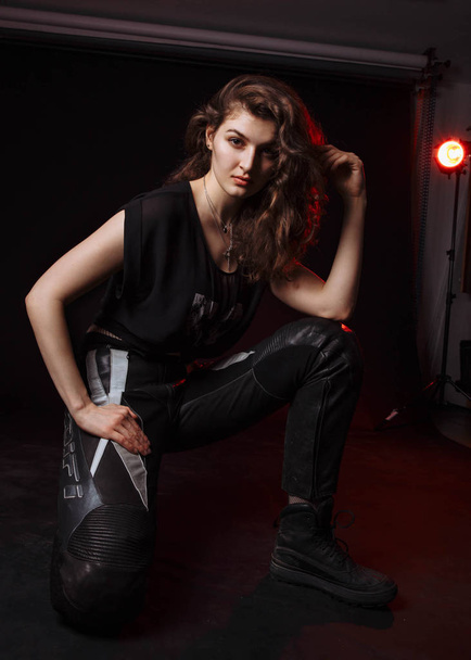 Girl biker with a piercing look. A red light falls on the girl. The shooting takes place in the studio. - Foto, Imagem