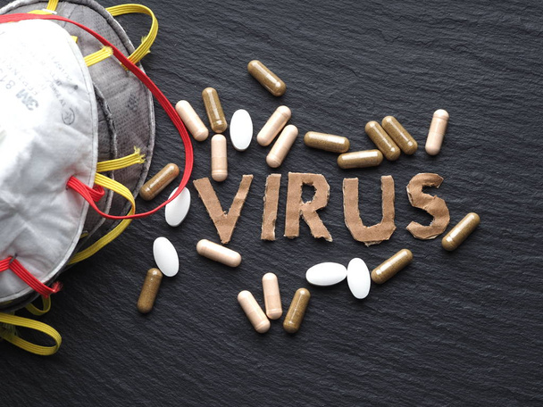 Text aus Coronavirus-Pappe auf schwarzem Hintergrund mit Medikamenten und Schutzmaske. Neues Coronavirus 2019-ncov, Mers-Cov. - Foto, Bild