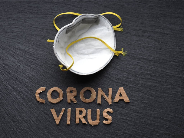 Frase de texto de papelão de coroonavírus em um fundo preto e uma máscara protetora de proteção contra vírus. Novo 2019-nCoV Coronavirus, MERS-Cov
. - Foto, Imagem