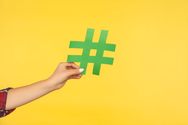 Closeup of female hand holding green paper hashtag symbol, hash  - Valokuva, kuva