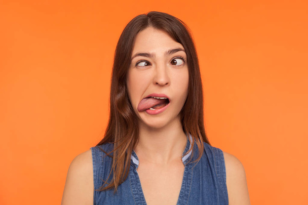 Closeup of silly dumb brunette woman demonstrating tongue and ma - 写真・画像