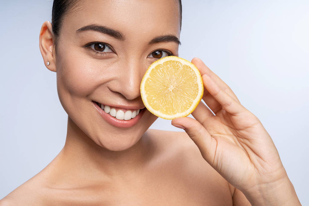 Positive delighted girl holding half of lemon - Zdjęcie, obraz