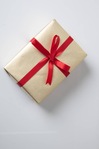 Golden gift box with red ribbon - Фото, зображення