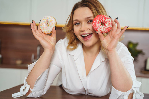 Vrolijke vrouwelijke persoon poseren met kleurrijke donuts - Foto, afbeelding