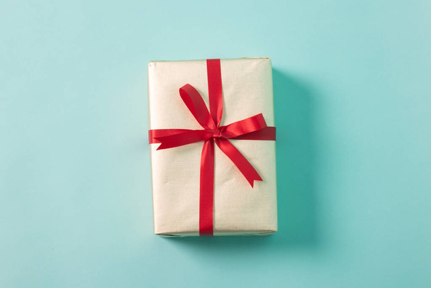 Golden gift box with red ribbon - Фото, зображення