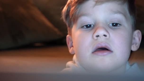 Kind spielt Videospiele und benutzt Computer. Junge blickt konzentriert auf Computerbildschirm. Futuristische RGB-Hintergrundbeleuchtung - Filmmaterial, Video