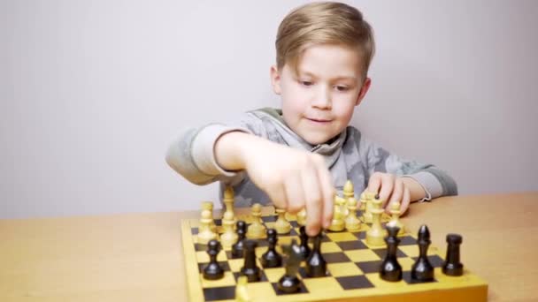 Gelukkige mooie jongen die schaak speelt. Kaukasisch kind concentreert zich tijdens het schaakbordspel. Witte achtergrond - Video