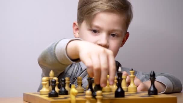 Gelukkige mooie jongen die schaak speelt. Kaukasisch kind concentreert zich tijdens het schaakbordspel. Witte achtergrond - Video