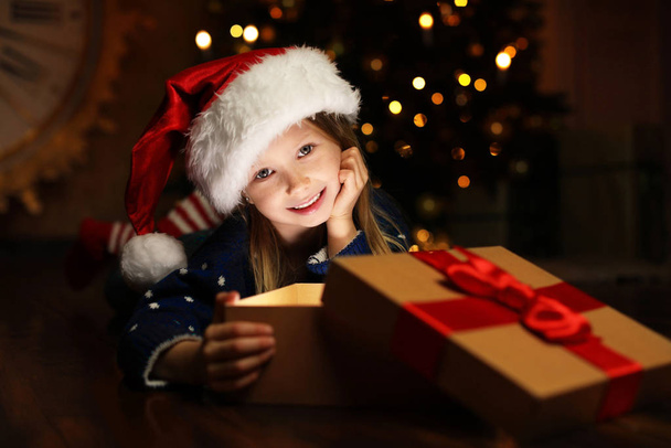 Aranyos gyermek nyitó mágia ajándék doboz közelében karácsonyfa éjszaka - Fotó, kép
