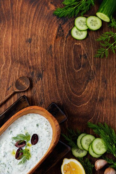 Traditional Greek sauce Tzatziki in olive wooden bowl on old rustic background. Top view. - Fotoğraf, Görsel