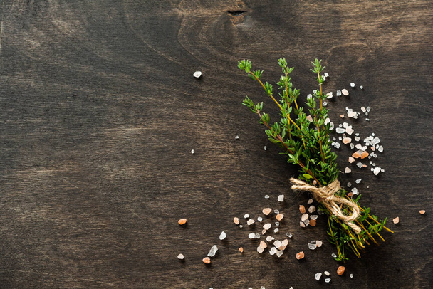 Herbs bunch thyme and condiments on old black wooden table. Thyme, sea salt and pepper. Top view with copy space. - 写真・画像