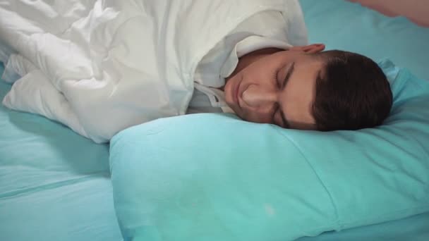 Ga naar bed, bedekt met een deken, een jongeman, close-up. Slaap lekker. - Video