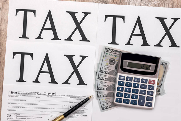 Formulario de impuestos 1040 con dólares, calculadora y pluma
 - Foto, imagen