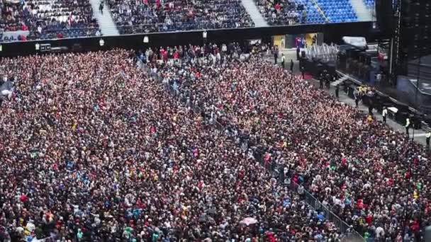Большая толпа людей на большом стадионе, готовящихся к рок-концерту, много людей
 - Кадры, видео