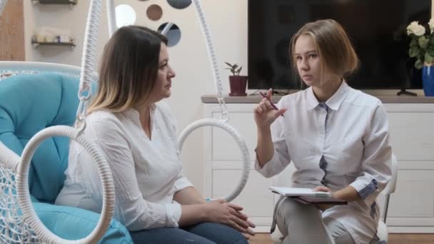 Woman visits young cosmetologist doctor. The doctor consults with the patient - Πλάνα, βίντεο