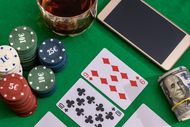 casino chips voor gokken, cognac en speelkaarten, geld en telefoon op groen - Foto, afbeelding