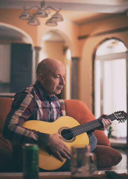 Oude man gitaarspelen thuis - Foto, afbeelding