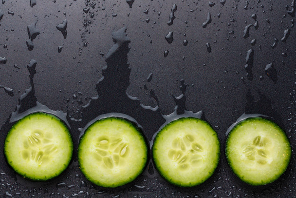 Isolated cucumber slices. Pieces of fresh cucumber isolated on black background - Fotó, kép