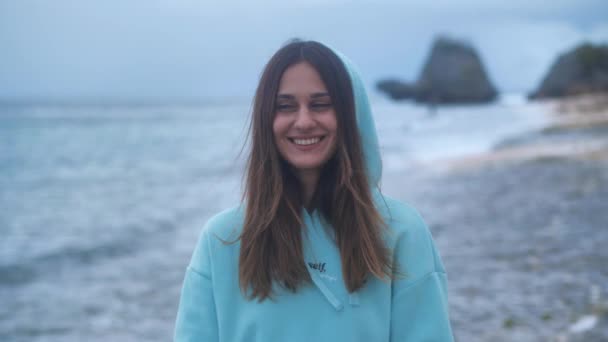 Muotokuva hipster nainen turkoosi huppari valtameren tausta hämärässä. 4 k.
 - Materiaali, video