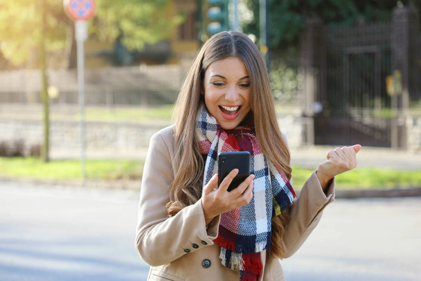 Successful business woman exults reading good news on mobile phone. Beautiful young business woman excited after achieved her goals. - Photo, Image