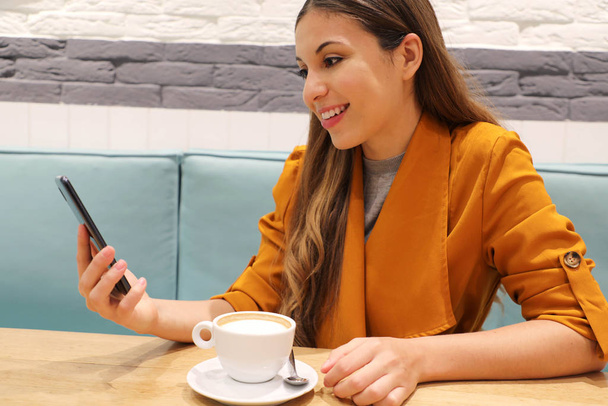 Cafe City lifestyle tyttö puhelimen juominen cappuccino lukeminen viesti älypuhelin app istuu sisätiloissa trendikäs kaupunkien kahvila
 - Valokuva, kuva
