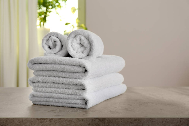 Stack of fresh towels on light grey stone table in bathroom - Zdjęcie, obraz