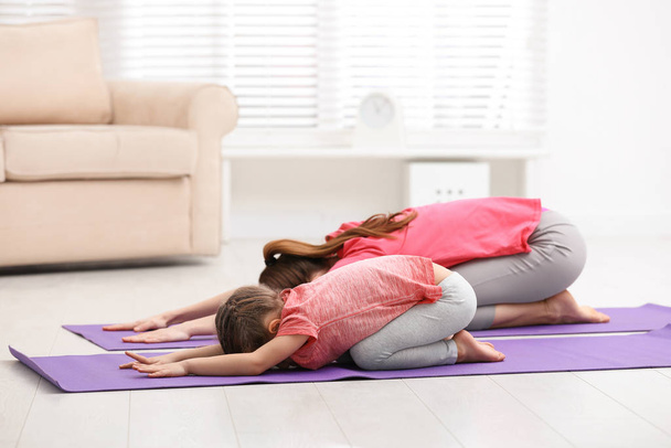 Young mother with little daughter practicing yoga at home - Foto, Imagem