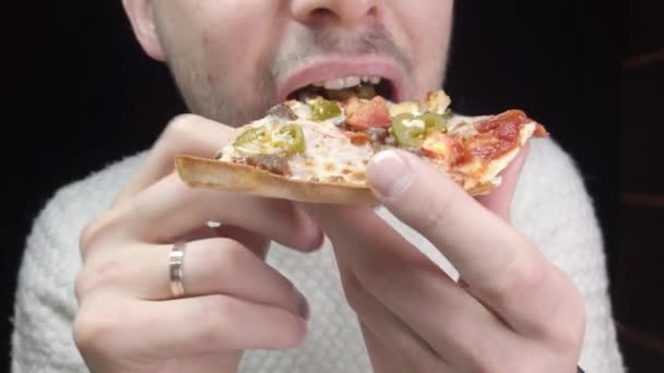 Close-up człowiek je pizzę na czarnym tle - Materiał filmowy, wideo