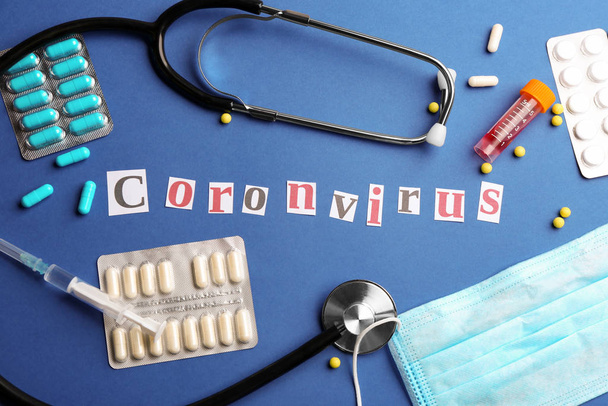 Flat lay composition with word CORONAVIRUS, stethoscope and medicine on blue background - Фото, зображення