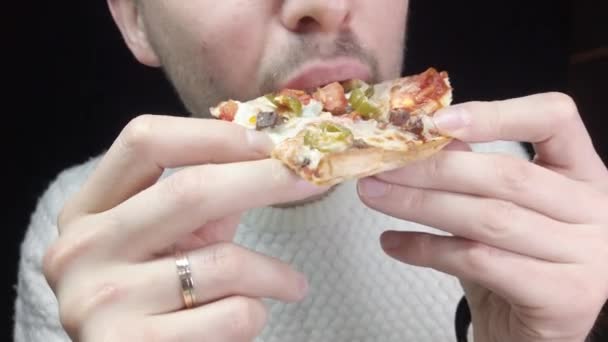 Close-up man eats pizza on black background - 映像、動画