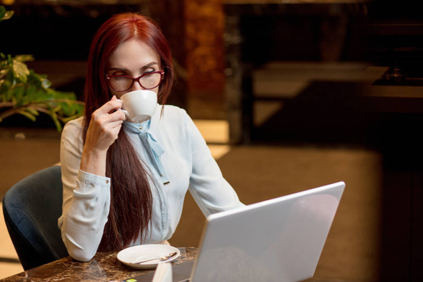 Business woman working at hotel lobby with laptop and drinking coffee - Foto, Bild