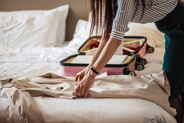 Woman in elegant clothes packing things into travel bag, departing from hotel - Foto, Imagen