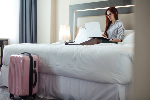 Elegant woman lying dressed on bed with laptop at the hotel room. - Foto, Imagen