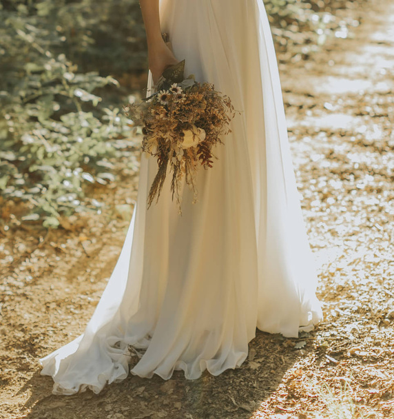 a noiva no vestido branco e um monte de flores em sua mão
 - Foto, Imagem