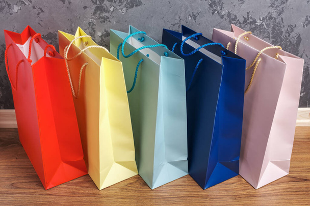 cinque shopping bag multicolore di carta sul pavimento in legno
 - Foto, immagini