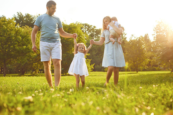 Happy family walking on the grass in the summer park. Children Protection Day. - Foto, imagen