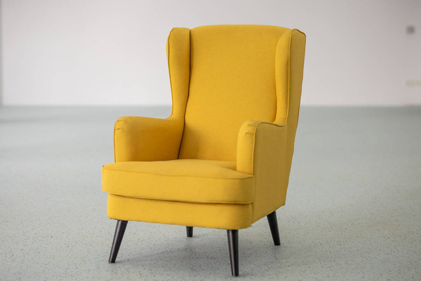 Gelber Sessel in der Mitte eines leeren Raumes - Foto, Bild