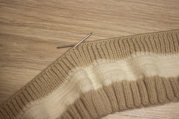 Tejido marrón sobre fondo claro. Agujas de punto y madejas de lana, tejer a mano. Enfoque selectivo
 - Foto, imagen