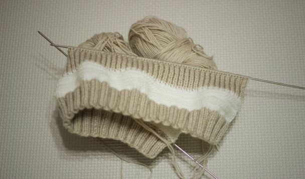 Tricot brun sur fond clair. Aiguilles à tricoter et écheveaux de laine, tricot à la main. Concentration sélective
 - Photo, image