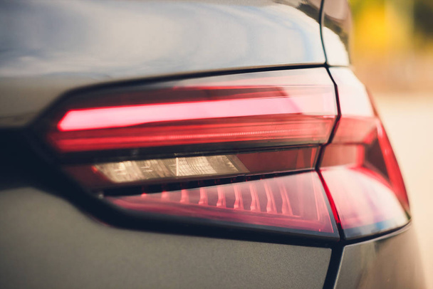 Detail of red metallized black rear car headlight in eye shape, with sun reflection in pupil. - Foto, Bild