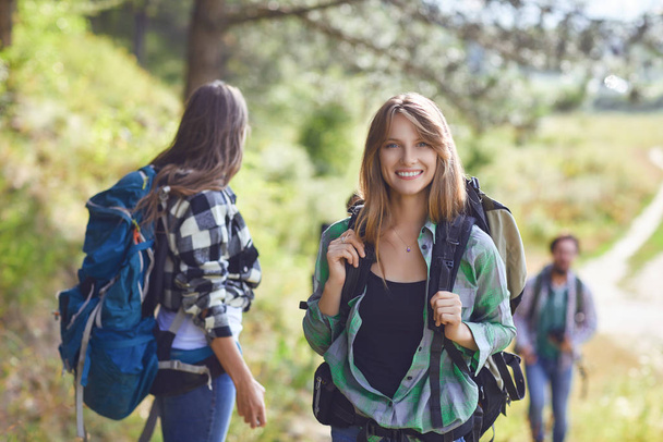 Girl with a backpack with friends, tourists walking in nature. - Fotoğraf, Görsel