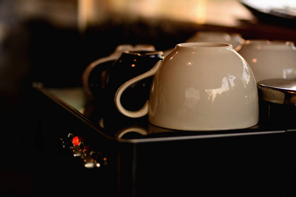 White cup on coffee machine in dark side - 写真・画像