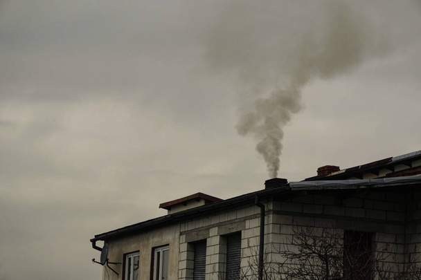 il fumo nero viene da camino di una casa contro cielo grigio, scaldandosi con carbone in inverno. problema ambientale dello smog nelle montagne Beskid, Zywiec, Cracovia. sistema di riscaldamento deve essere aggiornato
. - Foto, immagini