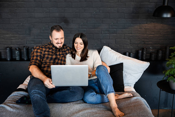 Couple with laptop in casual clothes on bed. - 写真・画像