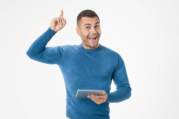 Happy young man in casual standing and using digital tablet with idea isolated over white background. - Foto, imagen