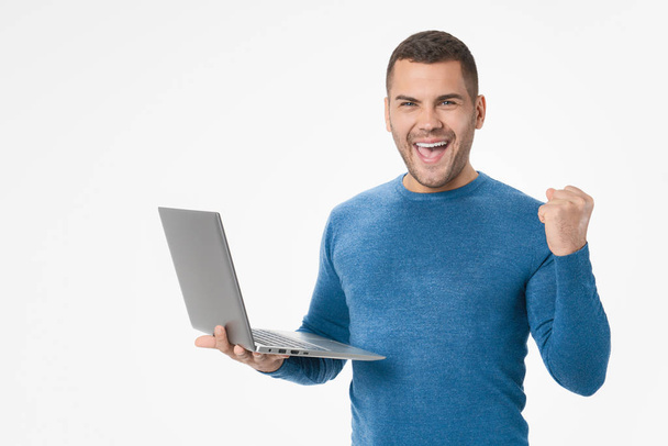 Portrait of joyful young man with laptop computer celebrating isolated over white background - Фото, зображення