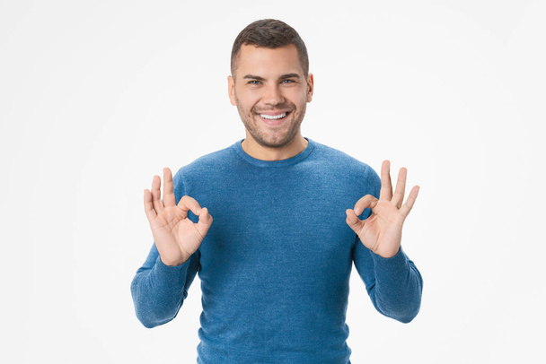 Portrait of smiling young man showing okay gesture isolated on white background - Foto, afbeelding