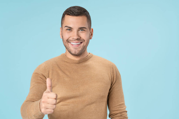 Cheerful handsome man showing thumb up isolated on blue background - Foto, afbeelding